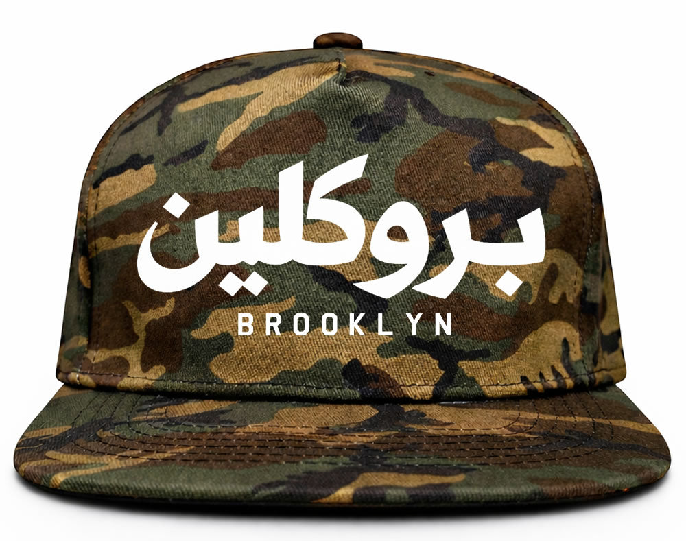 Camouflage cap with Arabic text and 'Brooklyn' printed on it against a white background
