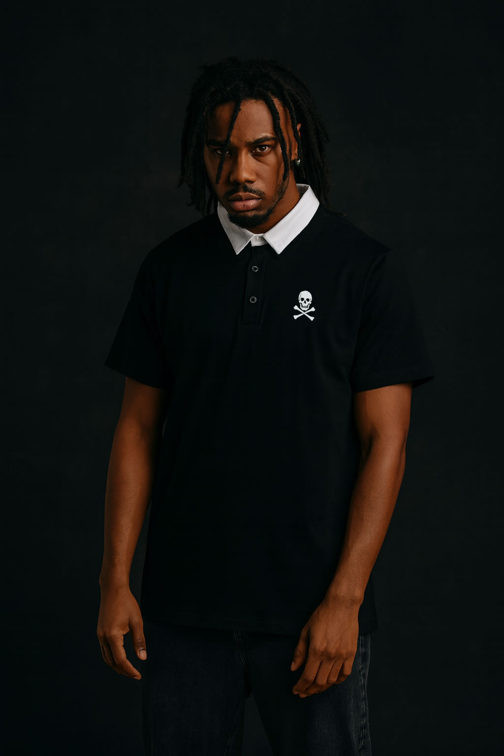 Man wearing a black polo shirt with a skull and crossbones design on a dark background