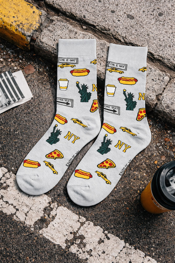 New York Icon socks with NYC themed designs on a concrete surface.