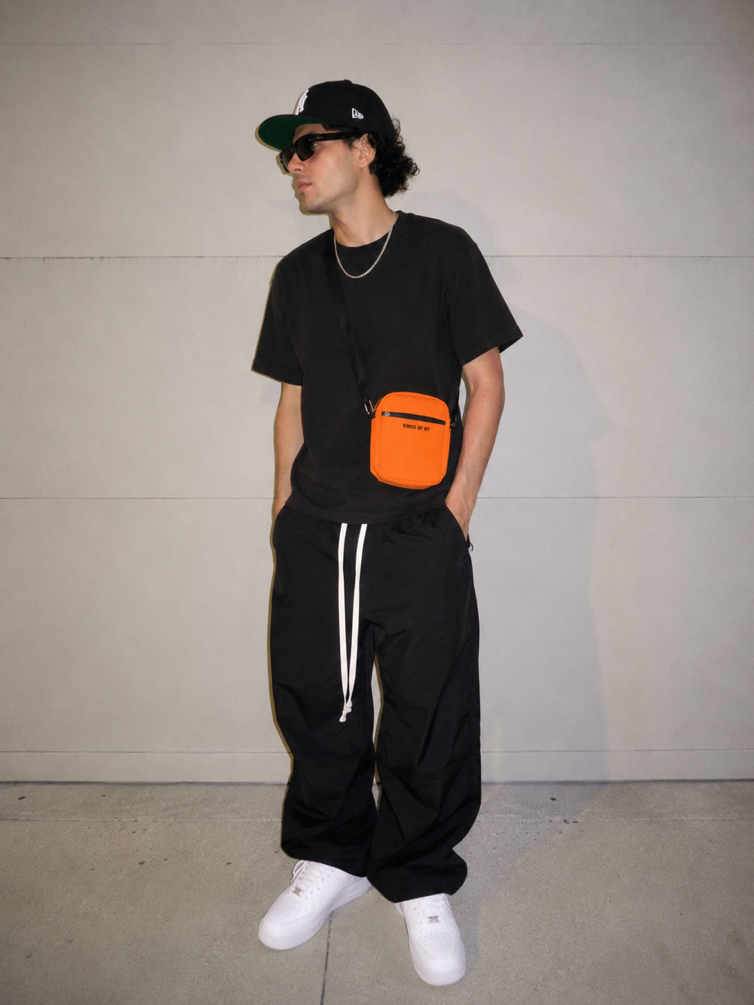 Model wearing a Men's Core Orange Crossbody Bag by KINGS OF NY