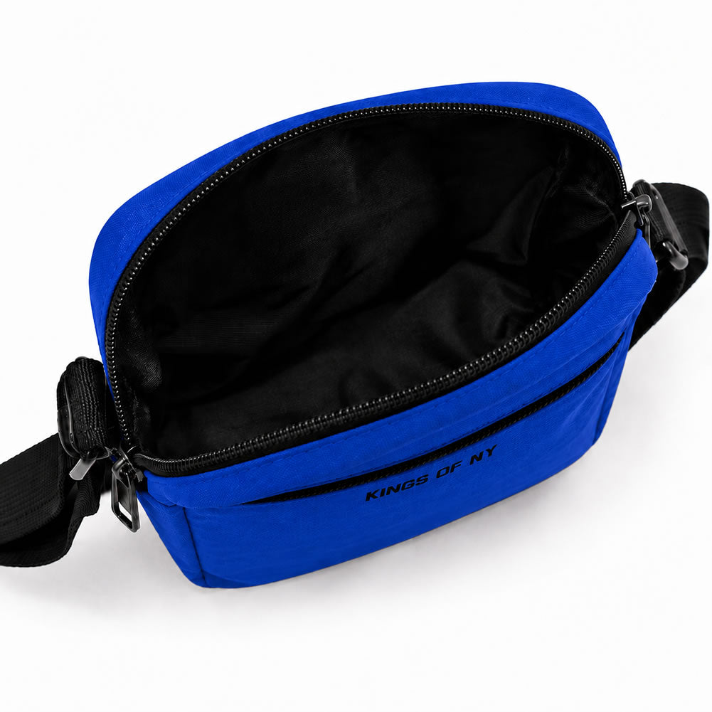 A bright blue crossbody bag with a black interior and black strap, shown open on a white background. The brand name 'KINGS OF NY' is printed in black on the front.